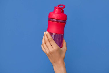 Female hand with bottle of water on blue background