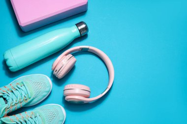 Sports water bottle with headphones and sneakers on blue background