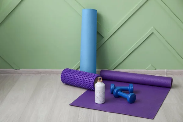 Sports water bottle with equipment on mat near green wall