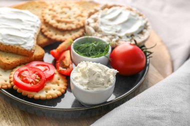 Plate with crackers, cream cheese, tomatoes and dill, closeup
