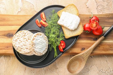 Plate of tasty crackers with cream cheese, dill and tomatoes on table