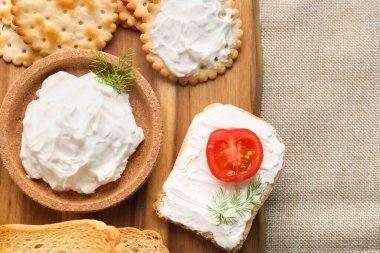 Bowl of tasty cream cheese and crackers on table, closeup