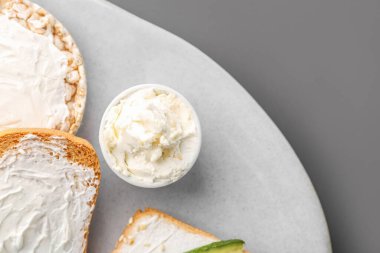 Plate with tasty crackers and cream cheese on grey background, closeup