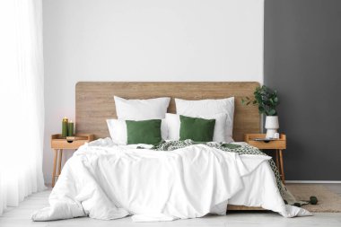 Interior of light bedroom with wooden tables and big bed