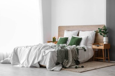 Interior of light bedroom with wooden tables and big bed