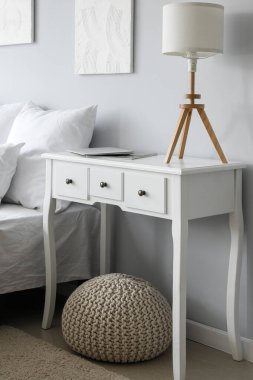 Lamp with laptop and magazine in white table in light bedroom