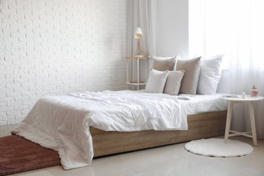 Interior of light bedroom with tables and and window