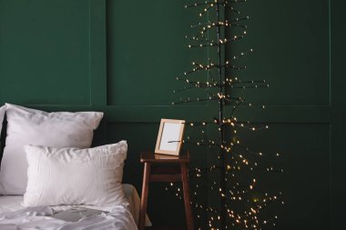 Bedside table with frame and glowing tree lamp in bedroom
