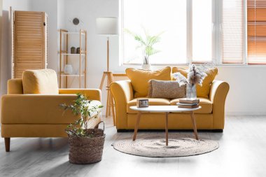 Interior of living room with yellow sofa, armchair and pampas grass in vase