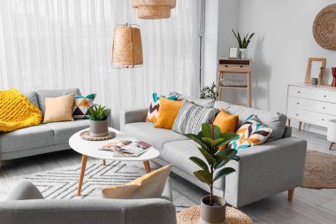 Beautiful interior of living room with cozy grey sofas, table and houseplants