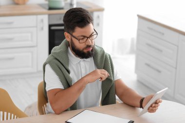 Erkek psikolog mutfakta hastayla görüntülü sohbet ediyor.