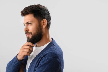 Thoughtful young bearded man on light background, closeup