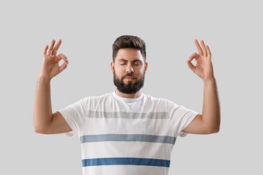 Handsome young man meditating on light background