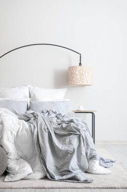 Interior of modern room with big bed, table and lamp