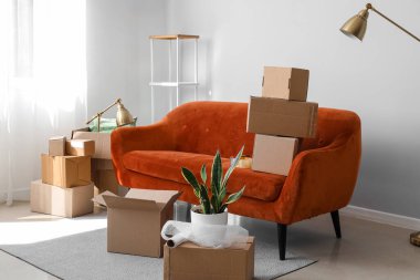 Cardboard boxes with red sofa in living room on moving day