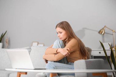 Sad young woman video chatting with psychologist on laptop at home