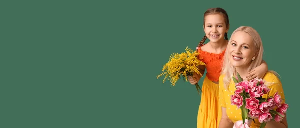 Little girl and her grandmother with flowers on green background with space for text