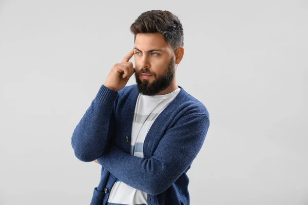 Thoughtful young bearded man on light background