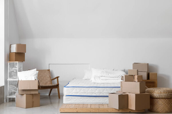 Картонные коробки с кроватью и креслом в спальне в день переезда