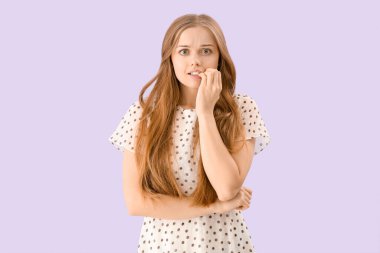 Leylak arka planında tırnak yiyen genç bir kadın.