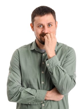 Beyaz arka planda tırnaklarını yiyen gömlekli yakışıklı bir adam.