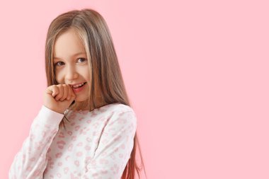 Little girl biting nails on pink background, closeup