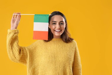 Young woman with flag of Ireland on yellow background