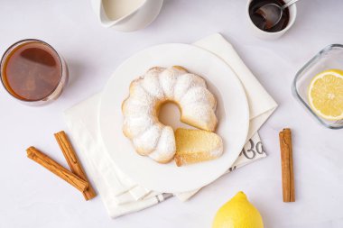 Plate with delicious cake and cinnamon on light background