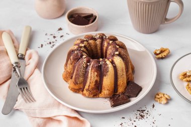 Plate with delicious cake and chocolate pieces on light background