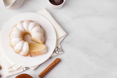 Plate with delicious cake and cinnamon on light background
