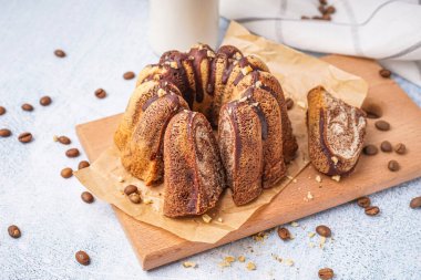 Wooden board with delicious cake and scattered coffee beans on light background