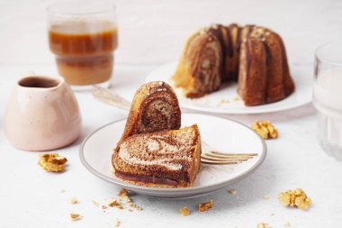 Plate with pieces of delicious cake and walnuts on light background