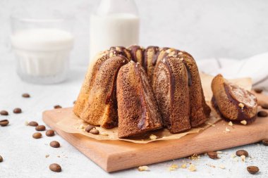 Wooden board with delicious cake and scattered coffee beans on light background, closeup