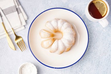 Plate with delicious cake and cup of tea on light background
