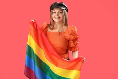 Beautiful young woman in hat with LGBT flag on red background