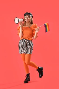 Beautiful young woman in hat with LGBT flag and megaphone on red background