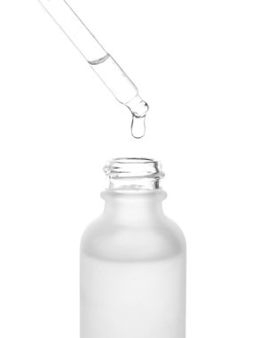 Dripping of serum from pipette into bottle on white background, closeup
