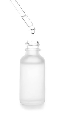 Dripping of serum from pipette into bottle on white background