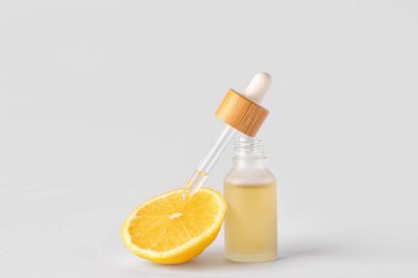 Bottle of serum with lemon on light background