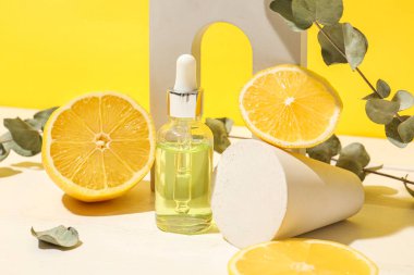 Composition with bottle of serum, fresh lemon, eucalyptus branches and decor on color background
