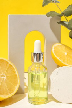 Bottle of serum, fresh lemon and decor on yellow background, closeup