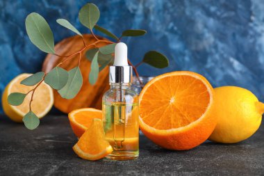 Bottle of healthy serum and fresh citrus fruits on table
