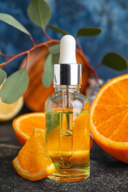 Bottle of healthy serum and fresh orange on table, closeup
