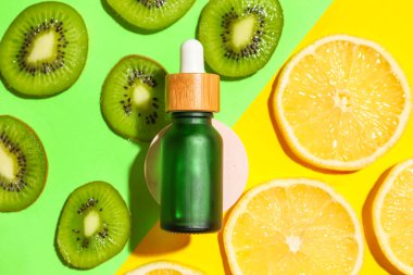 Composition with bottle of serum and fruit slices on color background