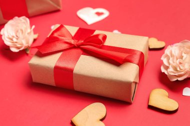Gift box with hearts and roses for Valentine's Day on red background, closeup