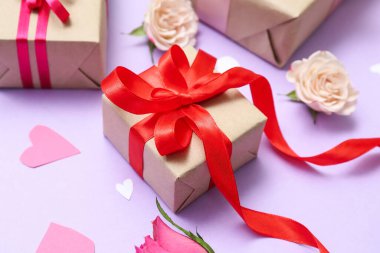 Beautiful gift tied with red ribbon and flowers on color background, closeup. Valentine's Day celebration