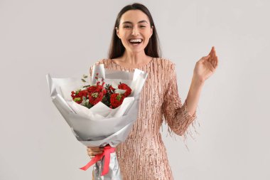 Young woman with bouquet of flowers on light background. Valentine's Day celebration