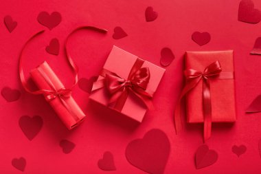 Gift boxes and paper hearts on red background. Valentine's Day celebration