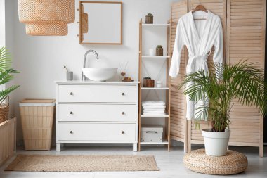 Interior of bathroom with ceramic sink, drawers and folding screen