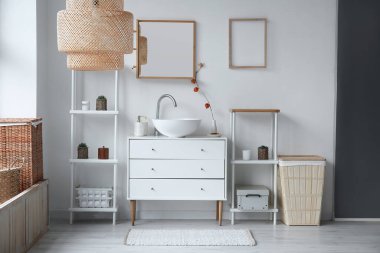 Interior of light bathroom with ceramic sink, drawers and shelving units